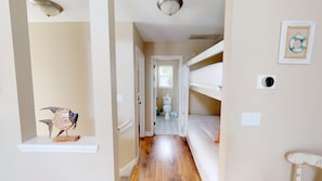 Cozy bedroom with a bunk bed, bedside table, and a bathroom with a toilet and window.