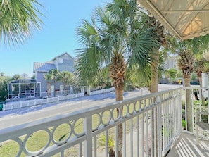Enjoy the serene views from this balcony with a railing featuring circular cutouts, overlooking lush palm trees.