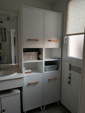 A compact kitchen with white cabinets, a sink, and a window with blinds.
