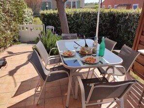An outdoor patio with a table set for two, surrounded by chairs.