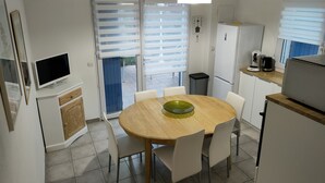 Una cucina compatta con tavolo, sedie, televisore e frigorifero.