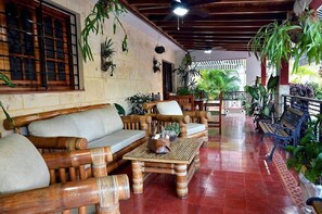 A wooden-floored lounge area with a sofa, a small table, and benches. - Villa Azzurra Cuba (Havana)