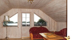 Una stanza con pareti in legno e soffitto a falde, arredata con un divano, un tavolo e una lampada.