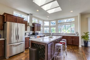 A modern kitchen with a large island, stainless steel appliances, and ample natural light from skylights.