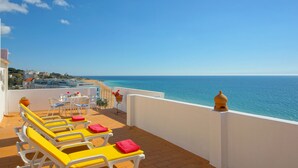 A terrace with yellow lounge chairs and a table, overlooking a coastal view. - Inn the Beach Apartments (Albufeira)
