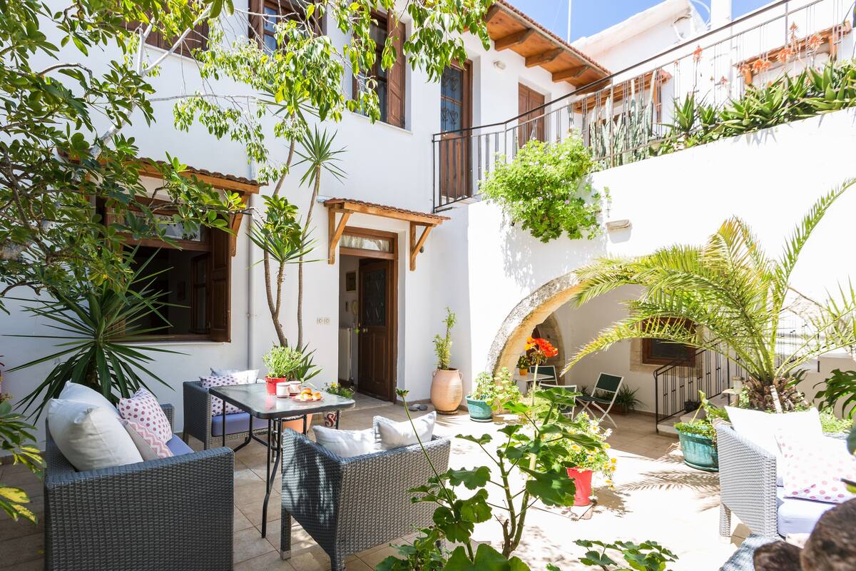 A courtyard with wicker furniture, potted plants, and a small table.