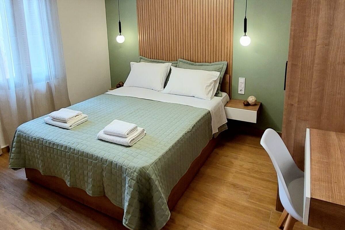 A neatly arranged bedroom with a bed, bedside table, chair, and a desk.