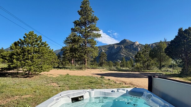 A hot tub with a clear view of mountains and trees in the background.
