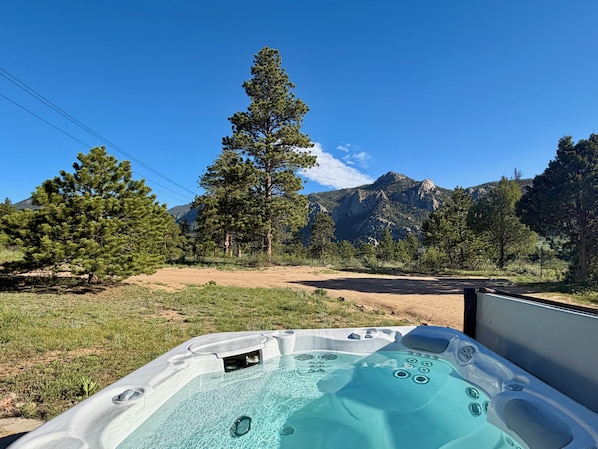A hot tub with a clear view of mountains and trees in the background.