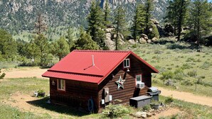 A wooden cabin with a red roof, a star decoration, and a small porch area.
