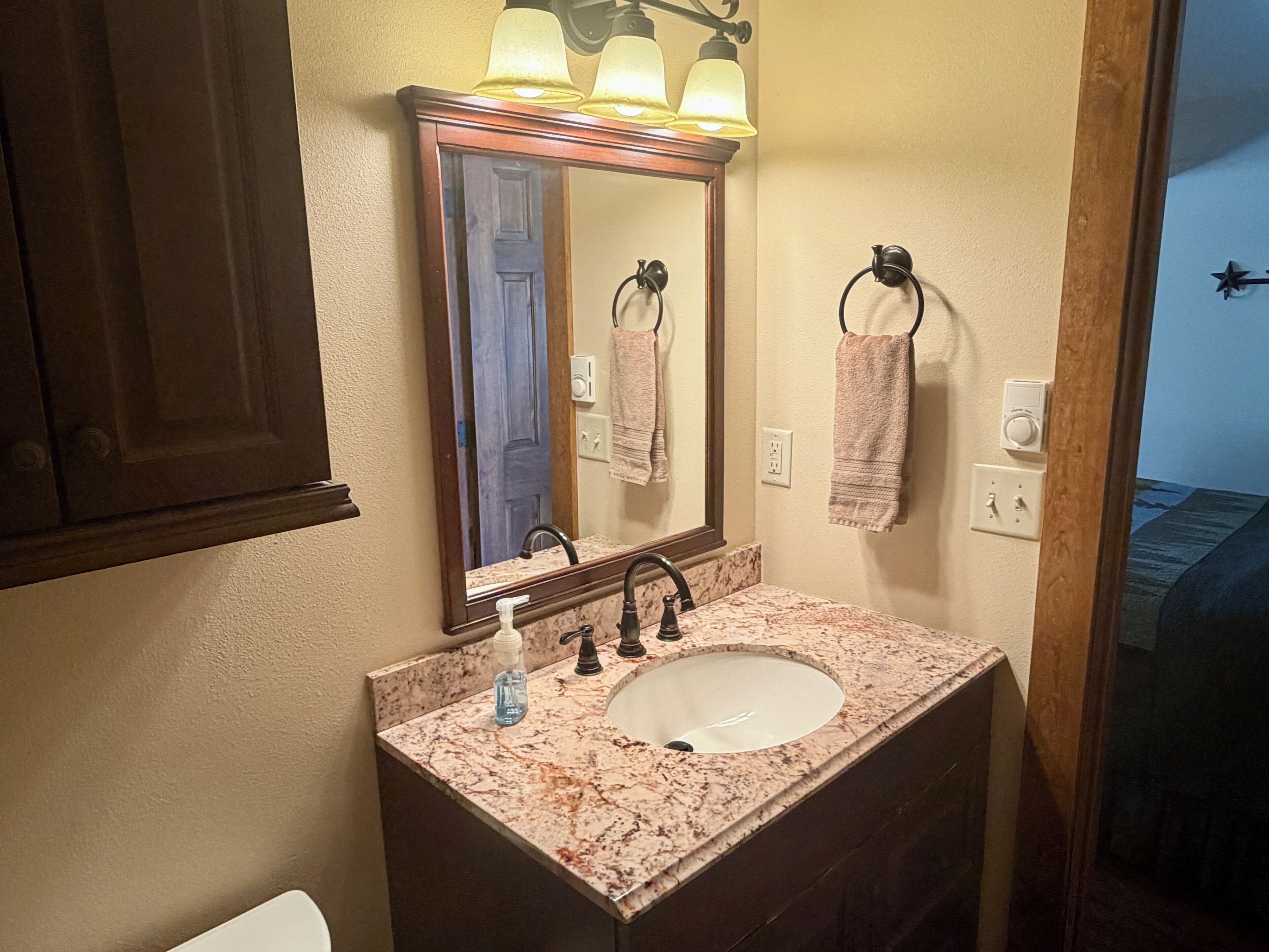 A bathroom with a sink, mirror, and towel rack.
