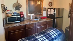 A compact kitchen with a microwave, coffee maker, and a refrigerator.