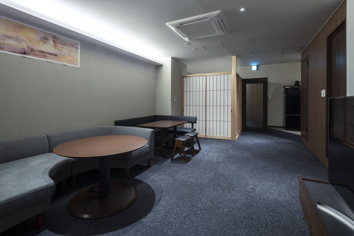 A modern interior with a sofa, round table, and chairs, a sliding door, and a television.