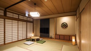A traditional Japanese room with tatami flooring, a low table with cushions, a shoji screen, and a hanging scroll. - Randor Residence Hiroshima Suites (Hiroshima)
