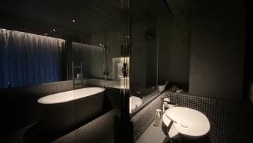 A modern bathroom with a freestanding bathtub, a separate sink area, and a glass-enclosed shower.