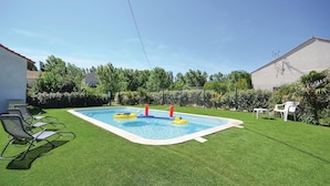 Ein Garten mit Swimmingpool, Rasen und Gartenmöbeln.
