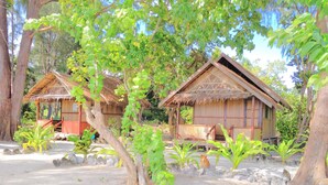 Two thatched-roof huts with wooden walls, surrounded by trees and plants. - Andau Homestay (Saprokren)