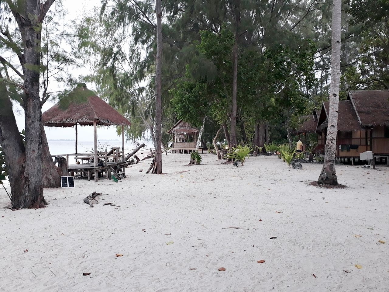 A beach with thatched-roof huts and a wooden deck area.