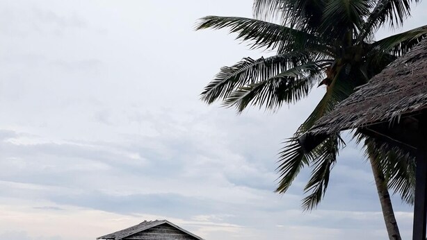 A beach with a wooden pier leading to a thatched-roof hut. - Andau Homestay (Saprokren)