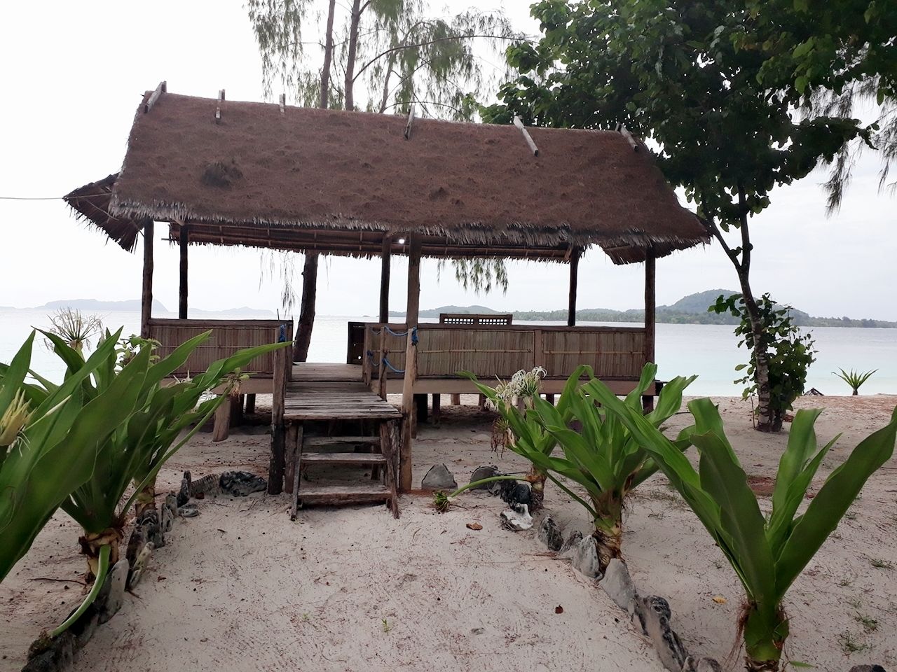A wooden structure with a thatched roof on a sandy beach, overlooking the sea.