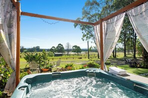 A hot tub with a view of a grassy field and trees. - The Studio Retreat perfect for a quiet romantic break. Pet friendly, hot tub. (Quorrobolong)