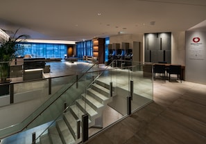 A modern hotel lobby with a glass staircase, seating areas, and a reception desk.