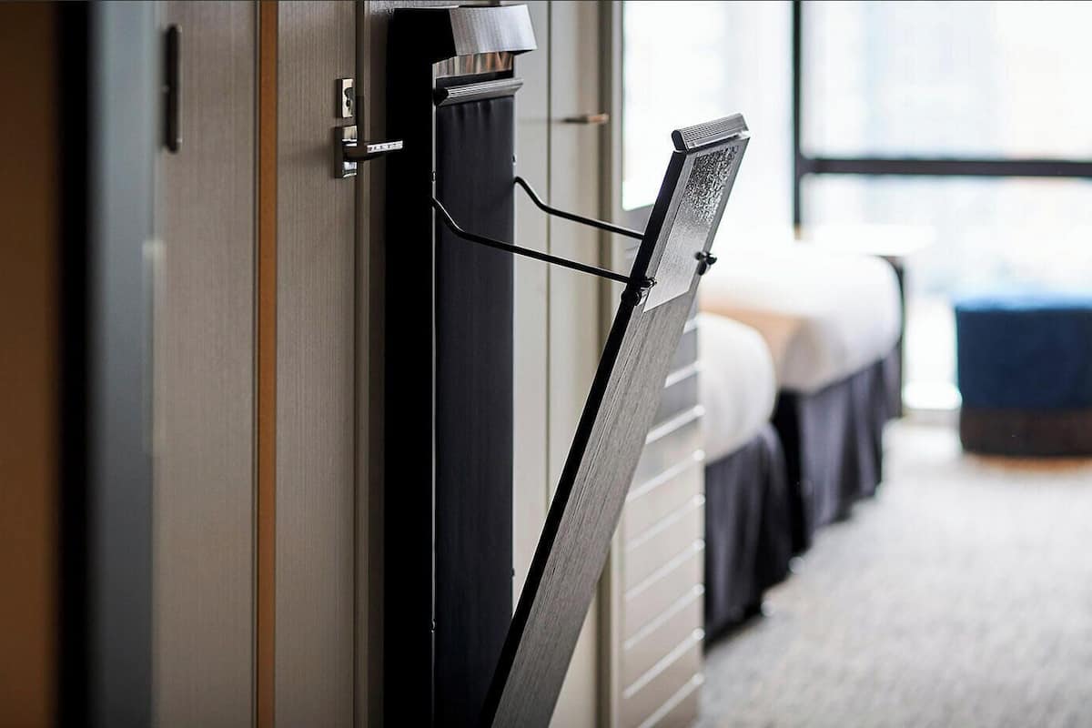 A hotel room with a bed, a desk, and a window.