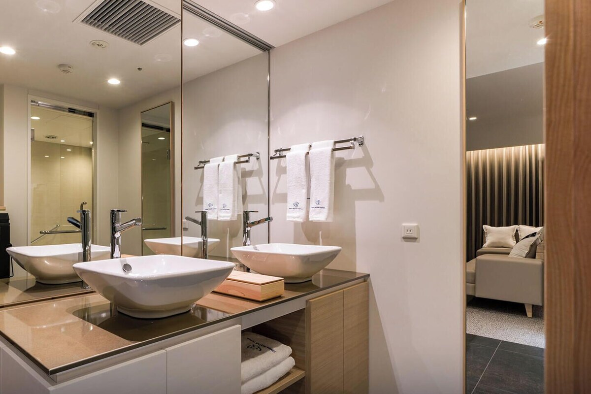 Een moderne badkamer met twee wasbakken, een grote spiegel en een open douche.
