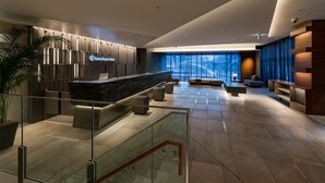 A modern hotel lobby with a reception desk, seating area, and a large window with curtains. - Daiwa Roynet Hotel Kyoto Terrace Hachijo PREMIER (Kyoto)