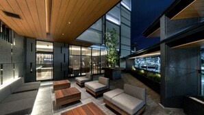 An outdoor seating area with sofas and wooden tables, large windows, and a modern architectural design. - Daiwa Roynet Hotel Kyoto Terrace Hachijo PREMIER (Kyoto)