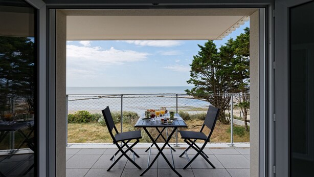 A patio with a table and chairs, overlooking a beach and ocean. - Facing the sea - 50 m from the  beach (La Guérinière)