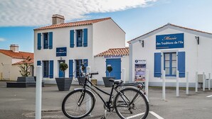 A building with a sign for 'Musée des Traditions de l'ile' and a bicycle parked in front. - Facing the sea - 50 m from the  beach (La Guérinière)