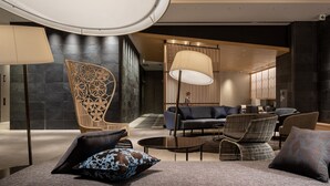 A modern lobby with a seating area featuring a sofa, chairs, and a coffee table. There is a decorative wall and a large lamp. - Mitsui Garden Hotel Ginza Gochome (Tokyo)