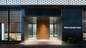 The exterior of Mitsui Garden Hotel with a modern design, featuring a wooden entrance, glass doors, and a patterned facade. - Mitsui Garden Hotel Ginza Gochome (Tokyo)