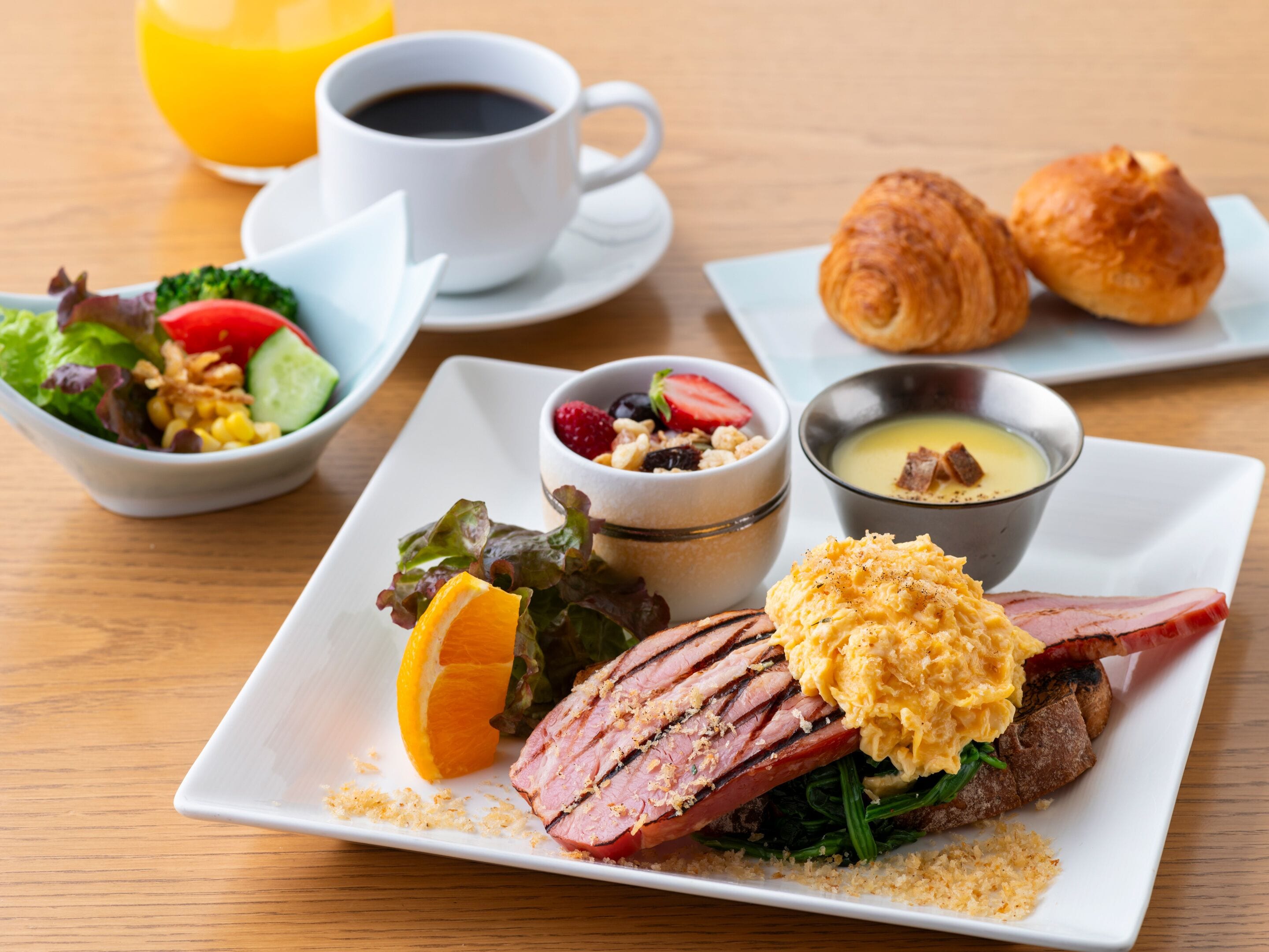A breakfast plate with ham, scrambled eggs, and a side salad.