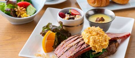 A breakfast plate with ham, scrambled eggs, and a side salad.