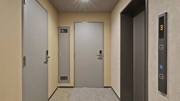 A hallway with three doors, a digital elevator control panel, and a patterned wall.