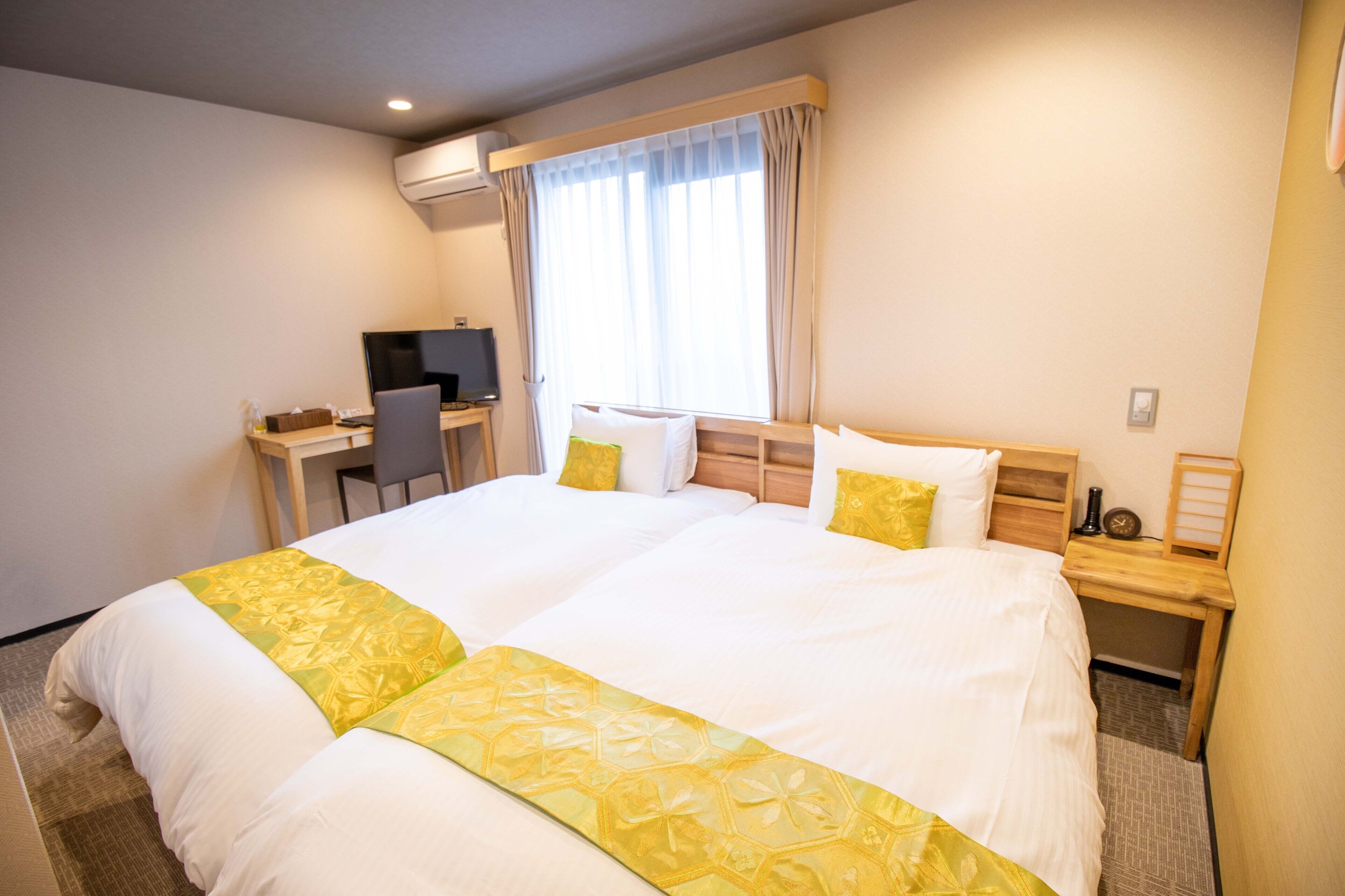 A hotel room with a large bed, a desk with a chair, and a TV.
