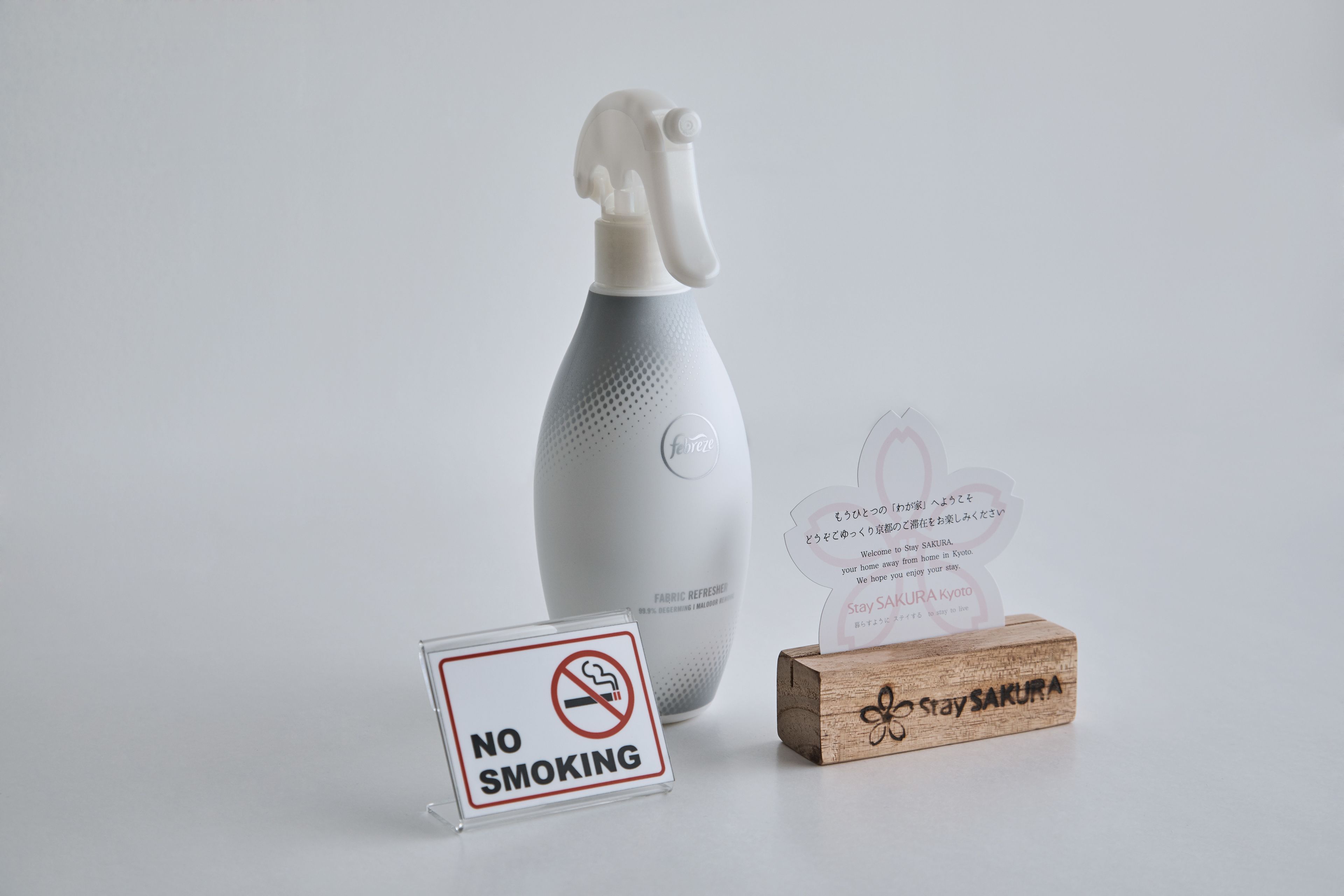 A no-smoking sign, a fabric refresher spray bottle, and a welcome card.