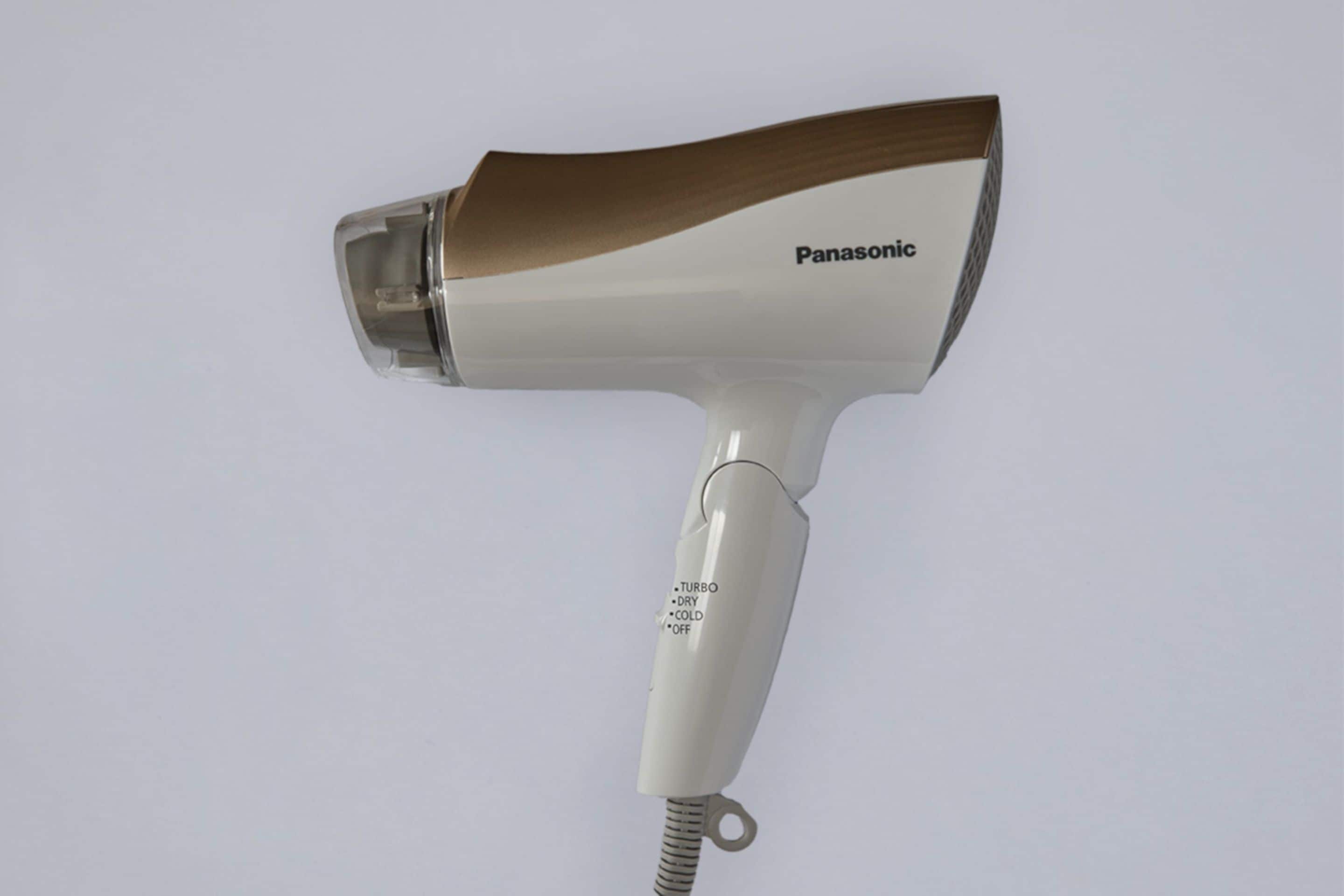 A Panasonic hair dryer with a white body and brown accents, featuring a control panel with settings like turbo, dry, cold, and off.