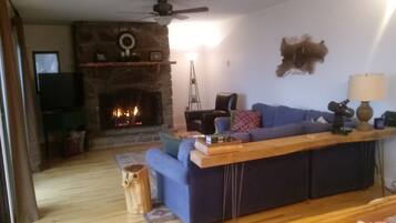 A living room with a stone fireplace, a blue sofa, a wooden coffee table, and a lamp.
