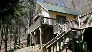 Eine zweistöckige Holzhütte mit einem Balkon und einer Treppe, die zum oberen Stockwerk führt.