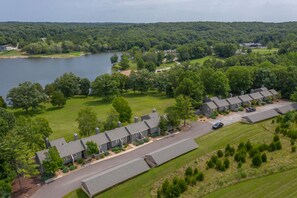 An aerial view of a residential area with a row of houses, a road, and a lake.
