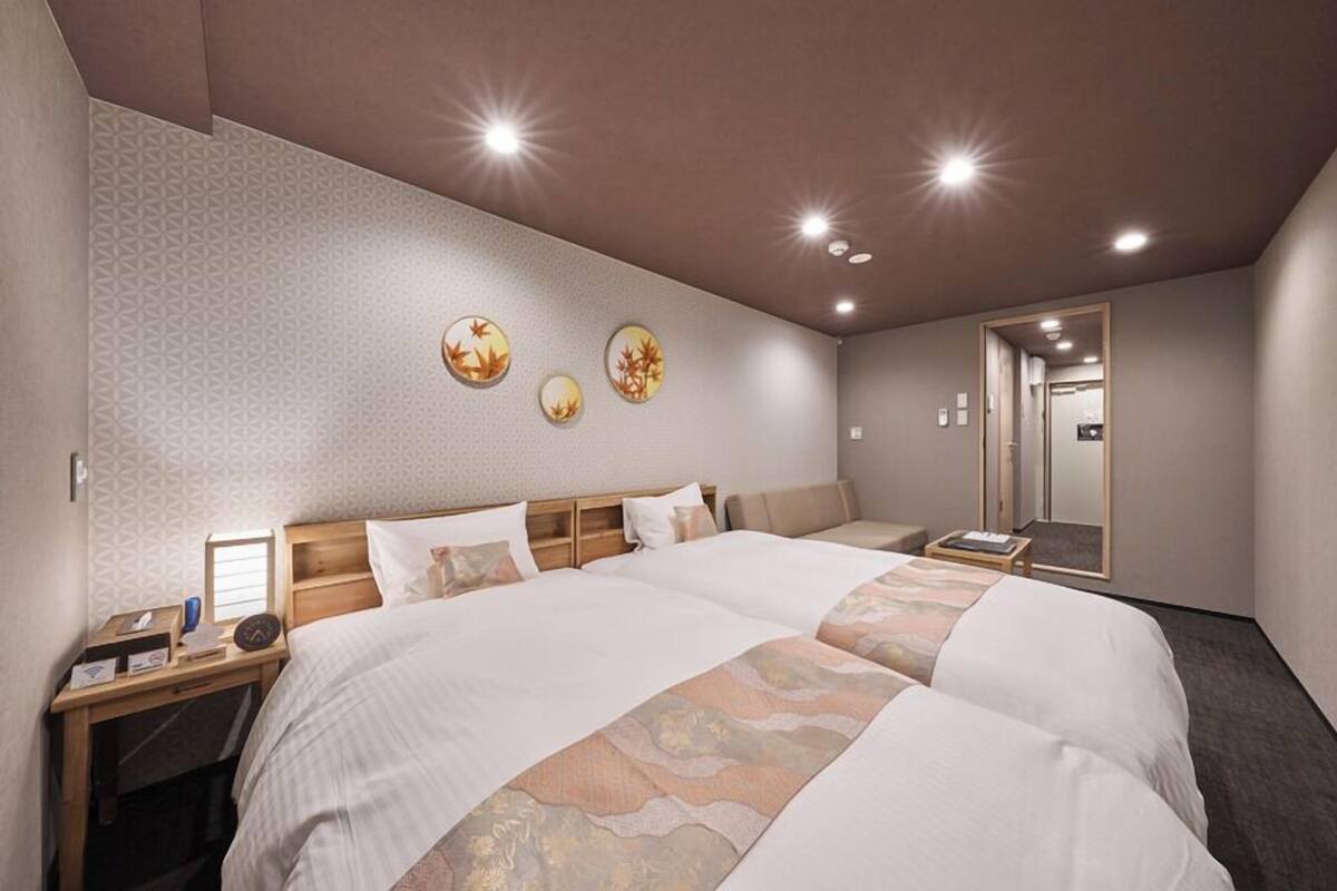 A hotel room with a large bed, a bedside table, a mirror, and a wall with decorative circular art pieces.