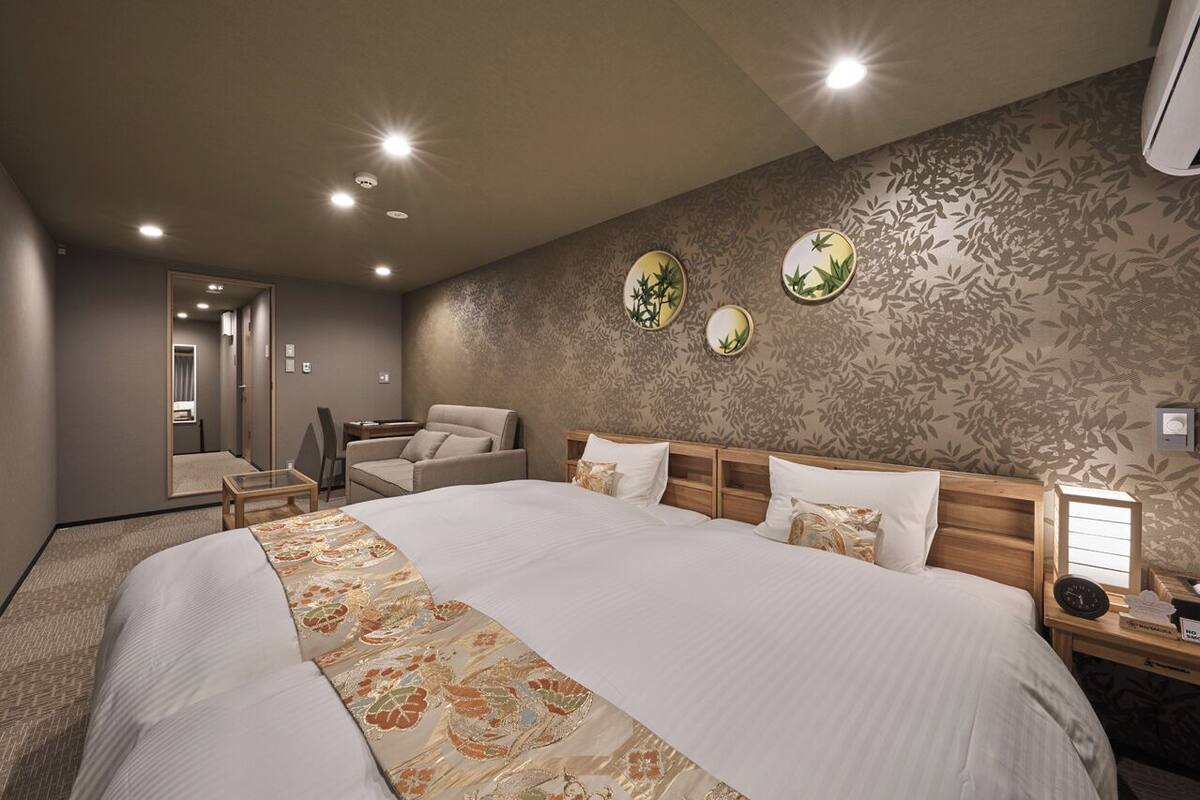 A hotel room with a large bed, a desk, a chair, and a mirror.