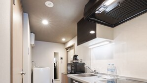 Una kitchenette compacta con microondas, lavamanos y refrigerador.