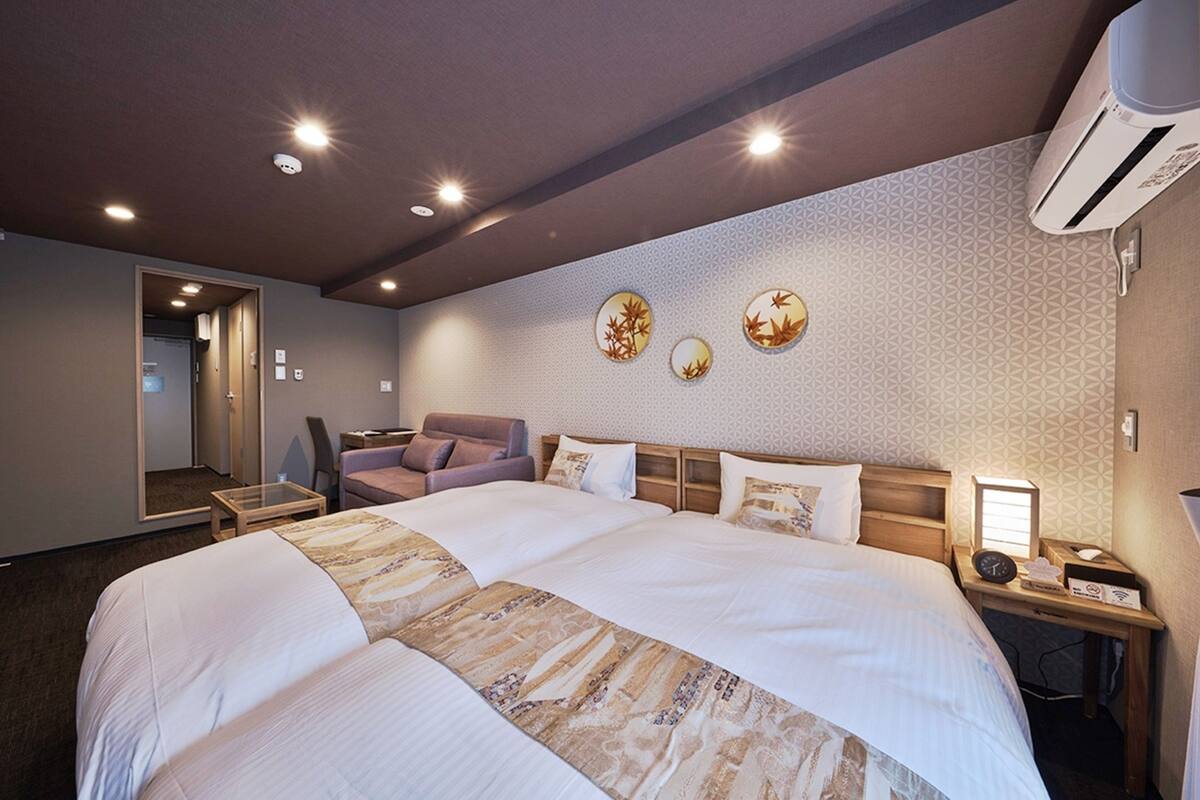 A hotel room with a large bed, a desk, a chair, and a mirror.