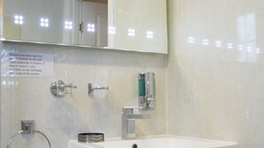 A bathroom with a white sink, a mirror, and a towel rack. - Apartment 4, Skye Holiday Apartments, Phoenix Flats (Portree)