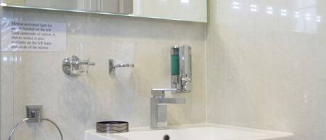 A bathroom with a white sink, a mirror, and a towel rack.