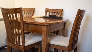 Een houten eettafel met vier stoelen, elk met een bekleed zitvlak.